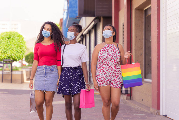 Freundschaftseinkäufe mit Schutzmasken gegen Coronavirus. Ein Bild von Mädchen mit Einkaufstaschen. Shopping, Tourismus und Viruskonzept. - Foto, Bild