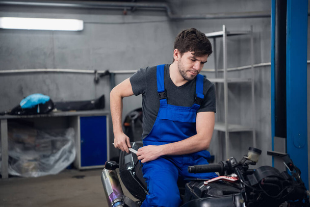 Un maquinista inspecciona una bicicleta mientras está sentado en ella - Foto, imagen