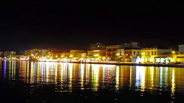 CHIOS, GREECE, SEPTEMBER 14, 2017. Panoramic night view of the harbor of greek island of Chios with reflections of colorful city lights in the water - Photo, image