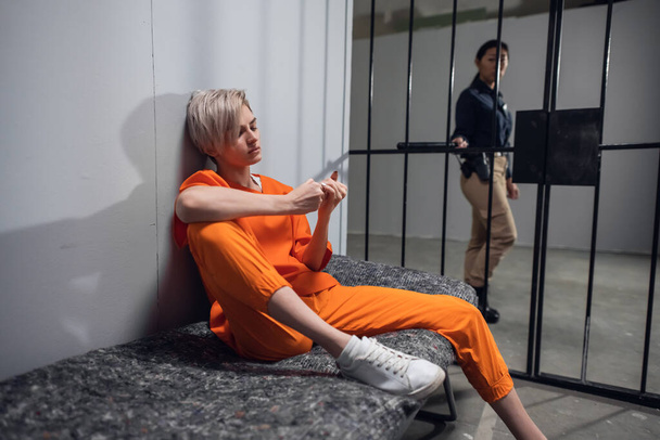 Une fille condamnée trafiquant de drogue en combinaison orange dans sa cellule sur une couchette de prison - Photo, image