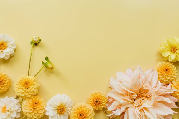 Orange, white, flowers dahlias on yellow pastel background. Flowers composition. Flat lay, top view, copy space. Summer, autumn concept. - Foto, imagen