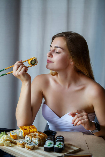 Girl holding chopsticks sushi roll. Young woman eating delicious fresh Japanese sushi. - Photo, Image