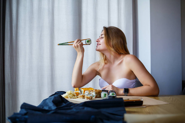Girl holding chopsticks sushi roll. Young woman eating delicious sushi. - Photo, image