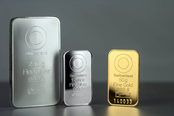 Gold- und Silberbarren mit unterschiedlichem Gewicht auf grauem Hintergrund. - Foto, Bild