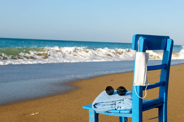 Καρέκλα μπλε με πετσέτα, γυαλιά στο φόντο ενός όμορφου κύματος στη θάλασσα - Φωτογραφία, εικόνα