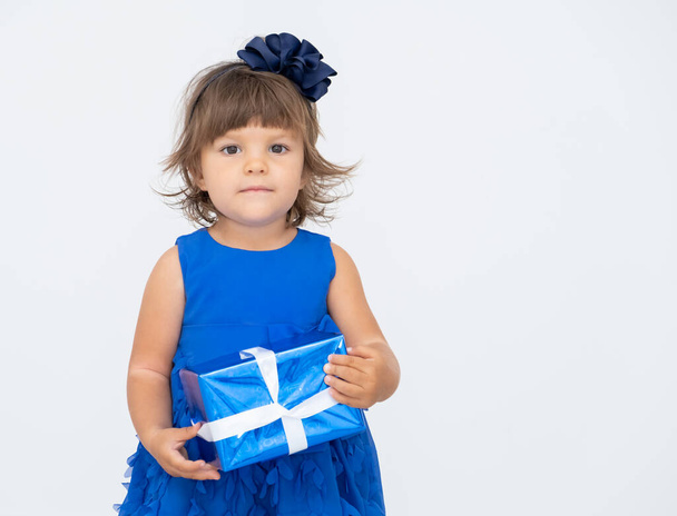 little brunette girl in blue dress holding gift box. - Foto, Bild