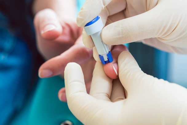 Infermiera foratura dito del paziente per spremere il campione di sangue per il test - Foto, immagini