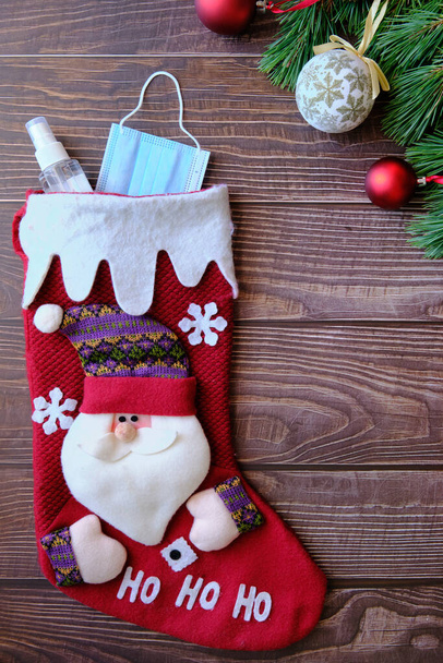 Χριστουγεννιάτικη κάλτσα με Άγιο Βασίλη με ιατρική μάσκα και αλκοολούχο gel. - Φωτογραφία, εικόνα