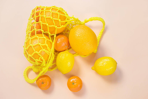 Pomarańcze, mandarynki, cytryny w żółtej torbie. Citrusy, witamina C. Zrównoważony rozwój, zero odpadów, wolne od tworzyw sztucznych koncepcje, wegetarianizm, zdrowa żywność. Widok z góry. - Zdjęcie, obraz