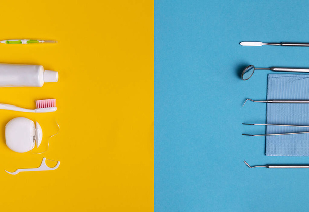 Zahnarztwerkzeuge und Dentalhygieneprodukte auf gelbem und blauem Hintergrund. Zahnseide, Pinsel und Mundwasser. Von oben betrachtet, flach gelegt. - Foto, Bild