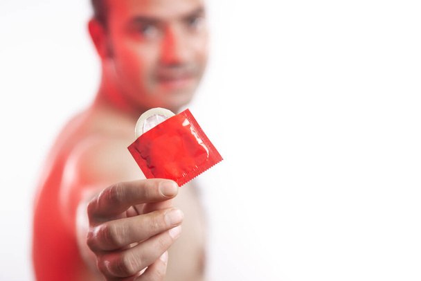 Επιλεκτική εστίαση, άνθρωπος που κρατά ένα κόκκινο προφυλακτικό σε λευκό φόντο, με χώρο αντίγραφο. - Φωτογραφία, εικόνα