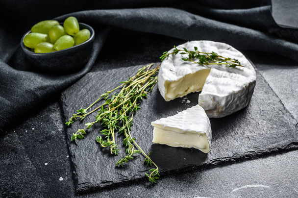French Brie cheese with grapes. Black background. Top view. - Photo, Image