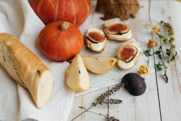 pumpkins, baguette with ricotta and figs on a white table. Vegan, vegetarian, healthy, comfort food concept. Autumn still-life. Halloween. Harvest. Postcard - Zdjęcie, obraz