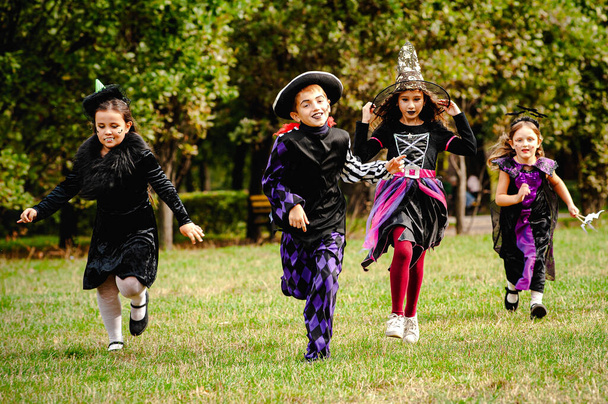 Enfants heureux en costumes d'Halloween courir sur la pelouse - Photo, image