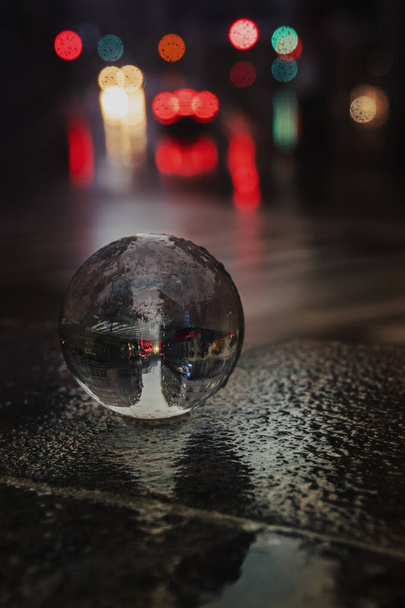 Bola de vidro na rua sob a chuva com algumas luzes do carro fora de foco no fundo - Foto, Imagem