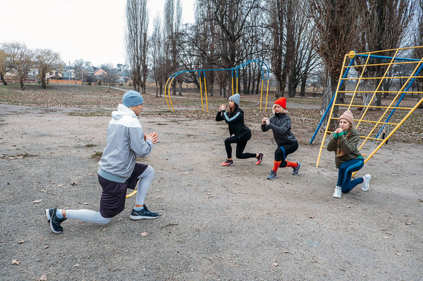 Csoportos fitnesz órák a szabadban. Nyilvános parkokban szervezett tornaórák. Három nő és egy férfi együtt edz a parkban. Egészség, wellness és közösségi koncepció. - Fotó, kép