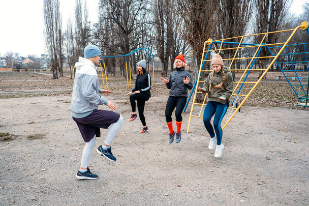 Lezioni di fitness di gruppo all'aperto. Lezioni di ginnastica organizzate nei parchi pubblici. Tre donne e un uomo che si allenano insieme nel parco pubblico. Salute, benessere e concetto di comunità. - Foto, immagini