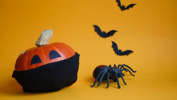 halloween pumpkin in black medical mask,spider and bats on orange background.concept championed Halloween holiday during Covid19 pandemic.Pumpkin protected against coronavirus during Covid19 epidemic - Photo, Image