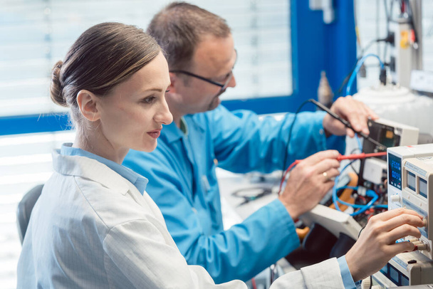 Test bankında iki elektronik mühendisi yeni bir ürünü ölçüyor. - Fotoğraf, Görsel