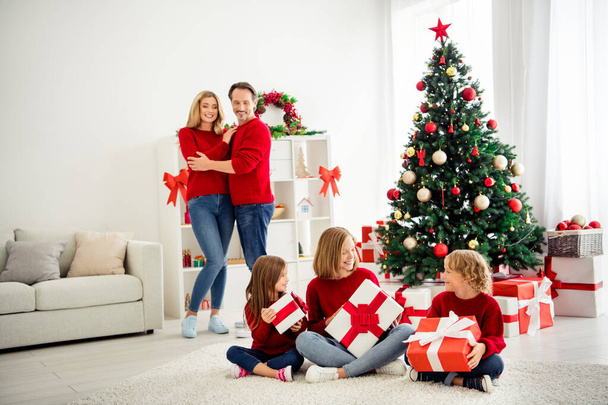大きな家族の写真5人が会う3人の小さな子供が贈り物を保持リボン弓好奇心親 × マスツリーは、自宅のリビングルームで赤いジャンパージーンズを着用多くの現在のボックス室内 - 写真・画像