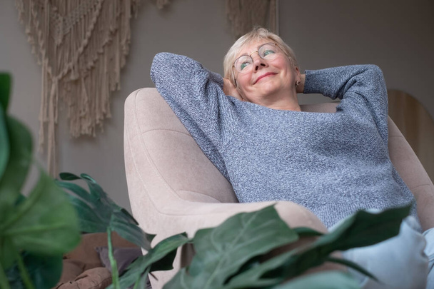 Europese vrouw rust, verheugt zich over goed positief nieuws, zit thuis op de bank - Foto, afbeelding