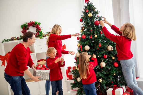 Photo of full big family five people gathering three small kids decorate x-mas tree dad help bring toys lights wear red jumper jeans in home living room many gift box mistletoe indoors - Foto, Imagem
