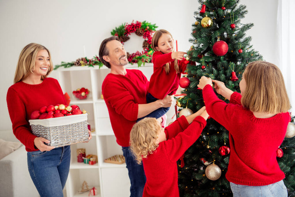 Photo of full big family five people gathering three small kids decorate x-mas tree mom smile bring box colorful toys garland lights wear red jumper jeans in home living room indoors - Foto, Imagen