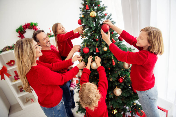 Photo of full big family five people gathering lovers parents three small kids decorate x-mas tree hold balls dad help daughter lights wear red jumper jeans in home living room indoors - Zdjęcie, obraz