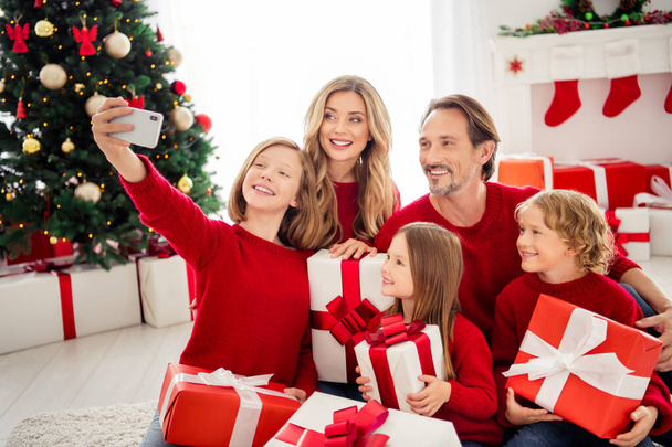Photo of full big family five people gathering three small kids hold boxes bow ribbon daughter make shoot selfie wear red jumper in decorated home living room x-mas tree indoors - Foto, afbeelding