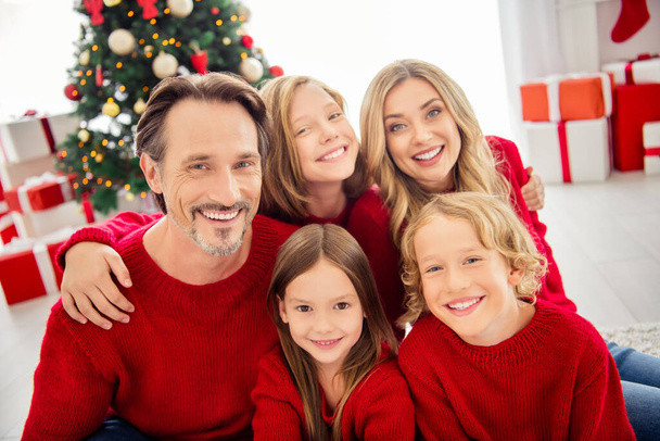 Closeup photo of full big family five people gathering three small kids cuddle shiny beaming smile sit floor wear red jumper in living room x-mas tree garland gift boxes indoors - Foto, Bild