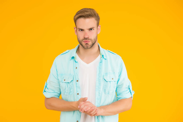 confident man has serious look wearing denim style outfit over yellow background, confidence and charisma - Valokuva, kuva