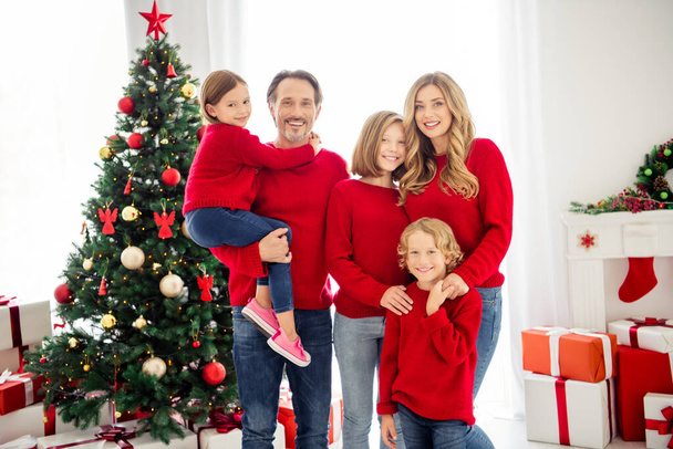 Photo of full family five people gathering couple lovers three small kids father hold cuddle daughter hold hands wear red sweater jeans in living room x-mas tree lights gift boxes indoors - Photo, Image