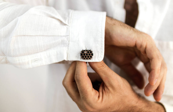 White male hands placing cufflinks on the sleeves of his white shirt. - Photo, Image