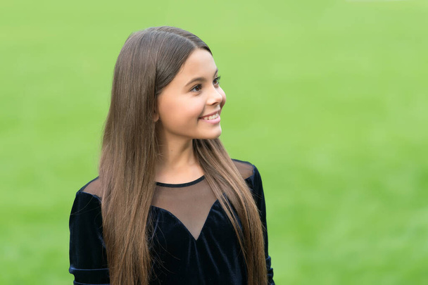 Happy little kid wear long brunette hair with beauty look green grass summer outdoors, future, copy space - Fotografie, Obrázek