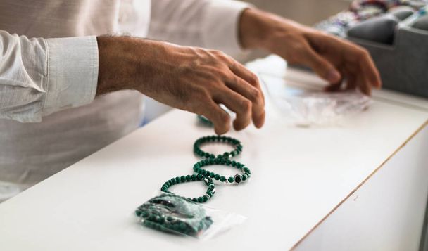 Ювелірний чоловік працює в своєму магазині, організовуючи різні види браслетів
. - Фото, зображення