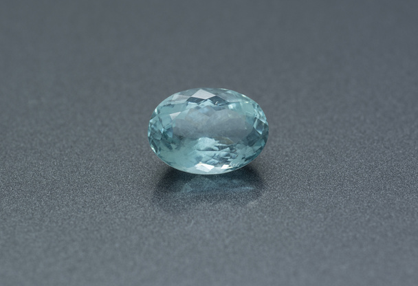 Rzeźbiony kamień szlachetny z błękitnej akwamaryny na szarym tle - Zdjęcie, obraz