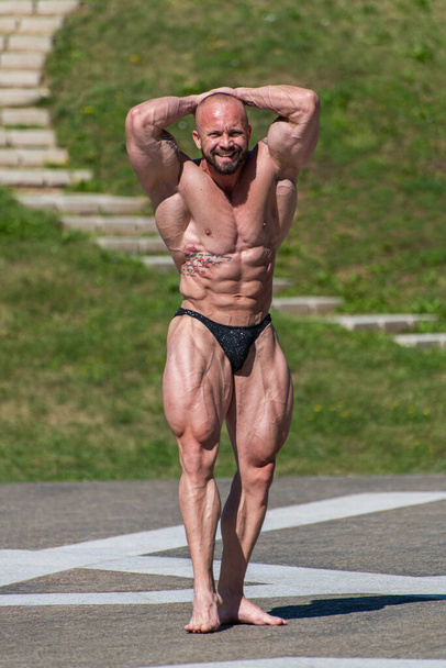 Powerful muscular bodybuilder in panties posing at the park.  Quadriceps and upper body contraction - 写真・画像