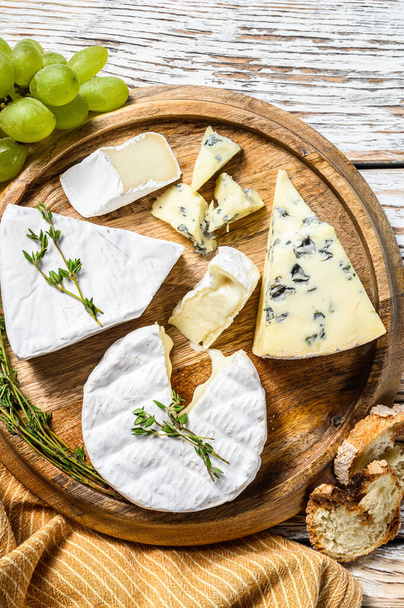 Cheese plate with Camembert, brie and blue cheese with grapes. White wooden background. Top view. - Photo, Image