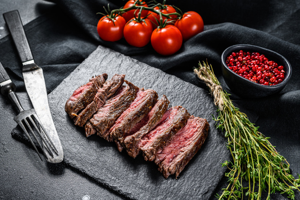 Grilled sliced skirt steak with seasonings and spices. Marbled meat. Black background. Top view. - Photo, Image