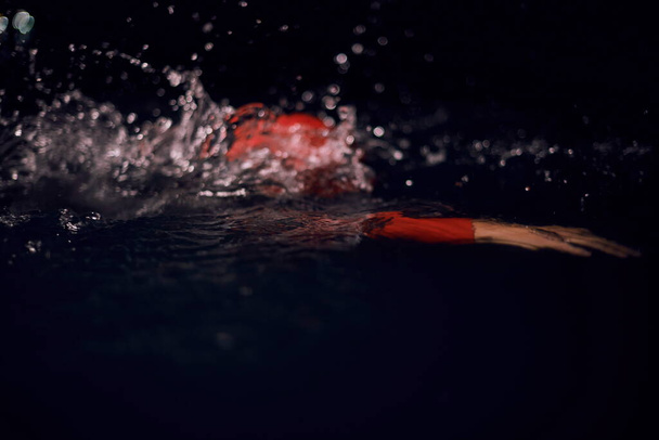 triathlon athlete swimming in dark night wearing wetsuit - Fotó, kép