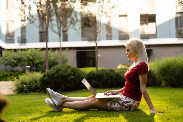 glimlachende jonge vrouw in het park met laptop - Foto, afbeelding