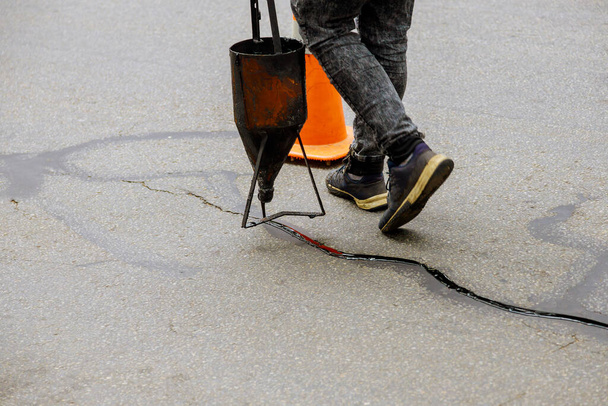 Afdichten gezamenlijke barst in asfalt wegdek restauratie werkzaamheden asfaltverbinding - Foto, afbeelding