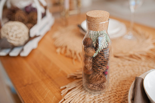 eco decoration with your own hands, a glass bottle with a cork filled with cones and natural wooden elements - Photo, Image