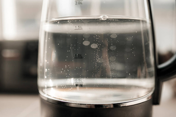 agua hirviendo con burbujas en una tetera transparente con indicadores de nivel - Foto, Imagen