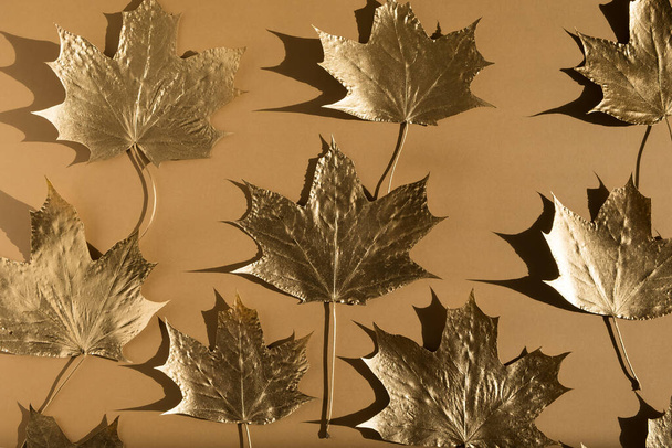 Autumn composition. Pattern made of autumn golden marple leaves on nude color background. Flat lay, top view, copy space - Foto, immagini