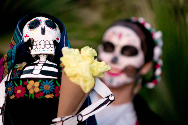 Mujer mexicana con colorido maquillaje tradicional del Día de los Muertos sosteniendo un cráneo mexicano tradicional con traje mexicano. - Foto, imagen