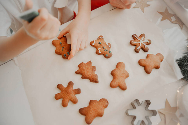 βαφή χεριών με βαφή από σωλήνα σε μπισκότα, έτοιμα μπισκότα σε λευκό τραπέζι με λαδόκολλα - Φωτογραφία, εικόνα