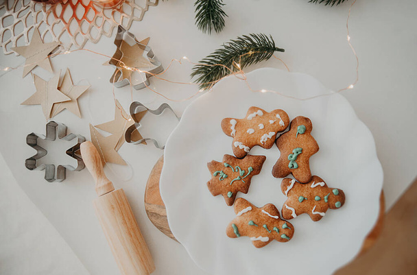 vicces házi süti formájában karácsonyfa, hópelyhek és egy ember egy fa fórumon a háttérben a karácsonyi dekoráció, égő gyertyák és koszorúk, függőleges fotó - Fotó, kép