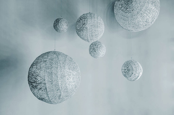 abstracte ruimte-installatie, zilveren bollen van verschillende afmetingen, alsof planeten op verschillende niveaus aan draden hangen - Foto, afbeelding