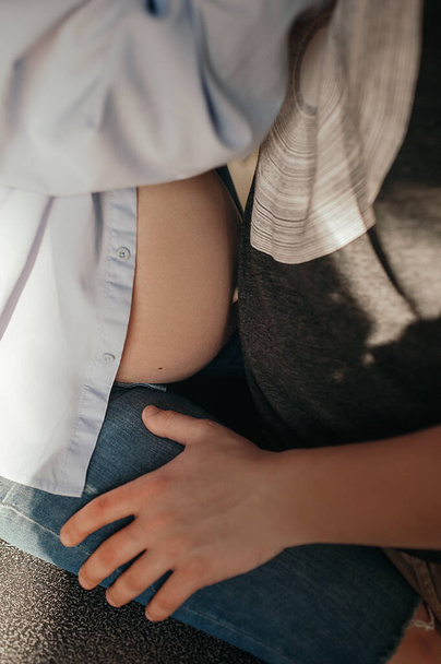 pancia incinta vicino ad un'altra persona, caldo abbraccio di due persone in attesa di un bambino, braccio a piedi - Foto, immagini